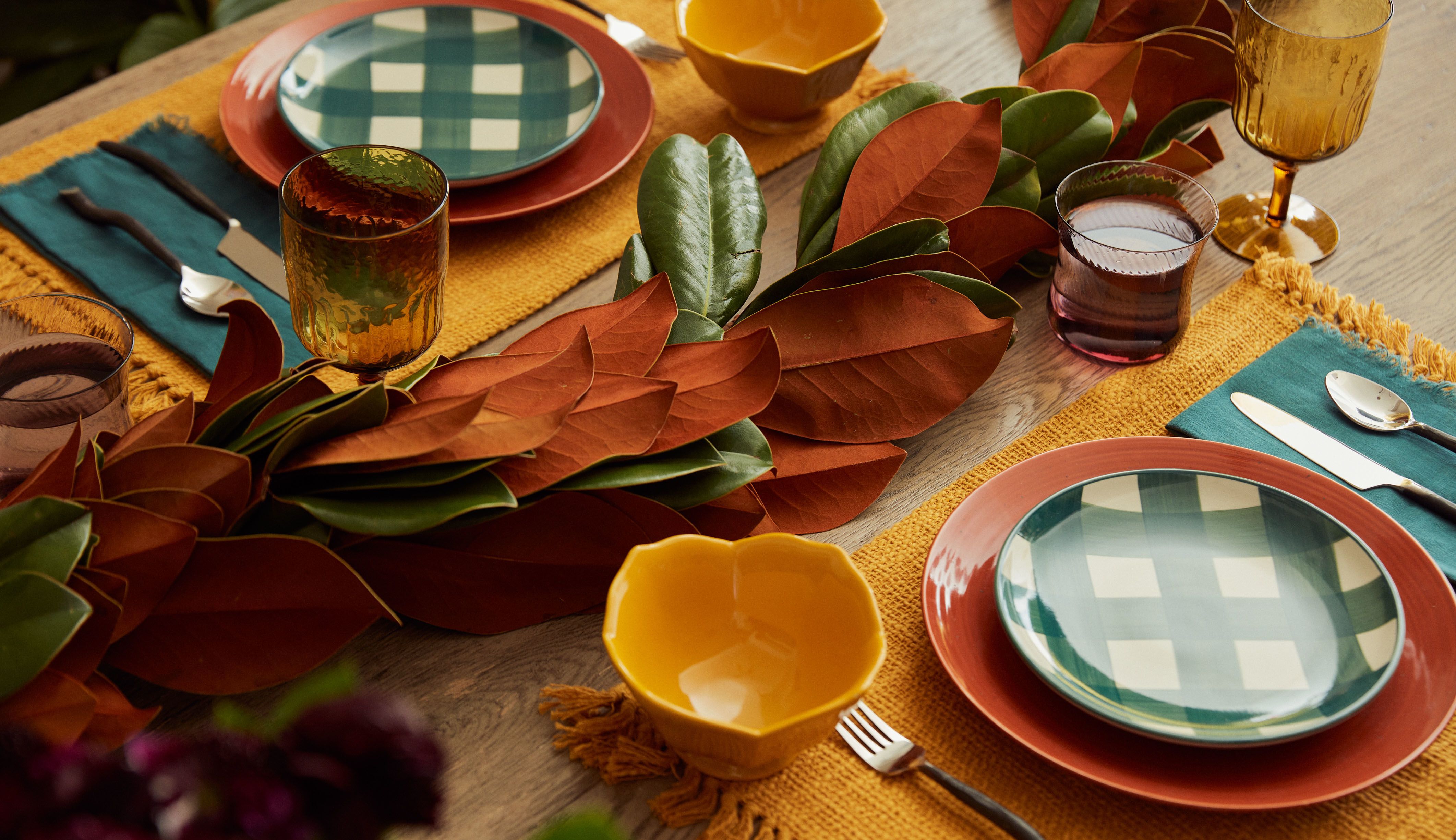 Table set for Thanksgiving with magnolia leaf runner centerpiece