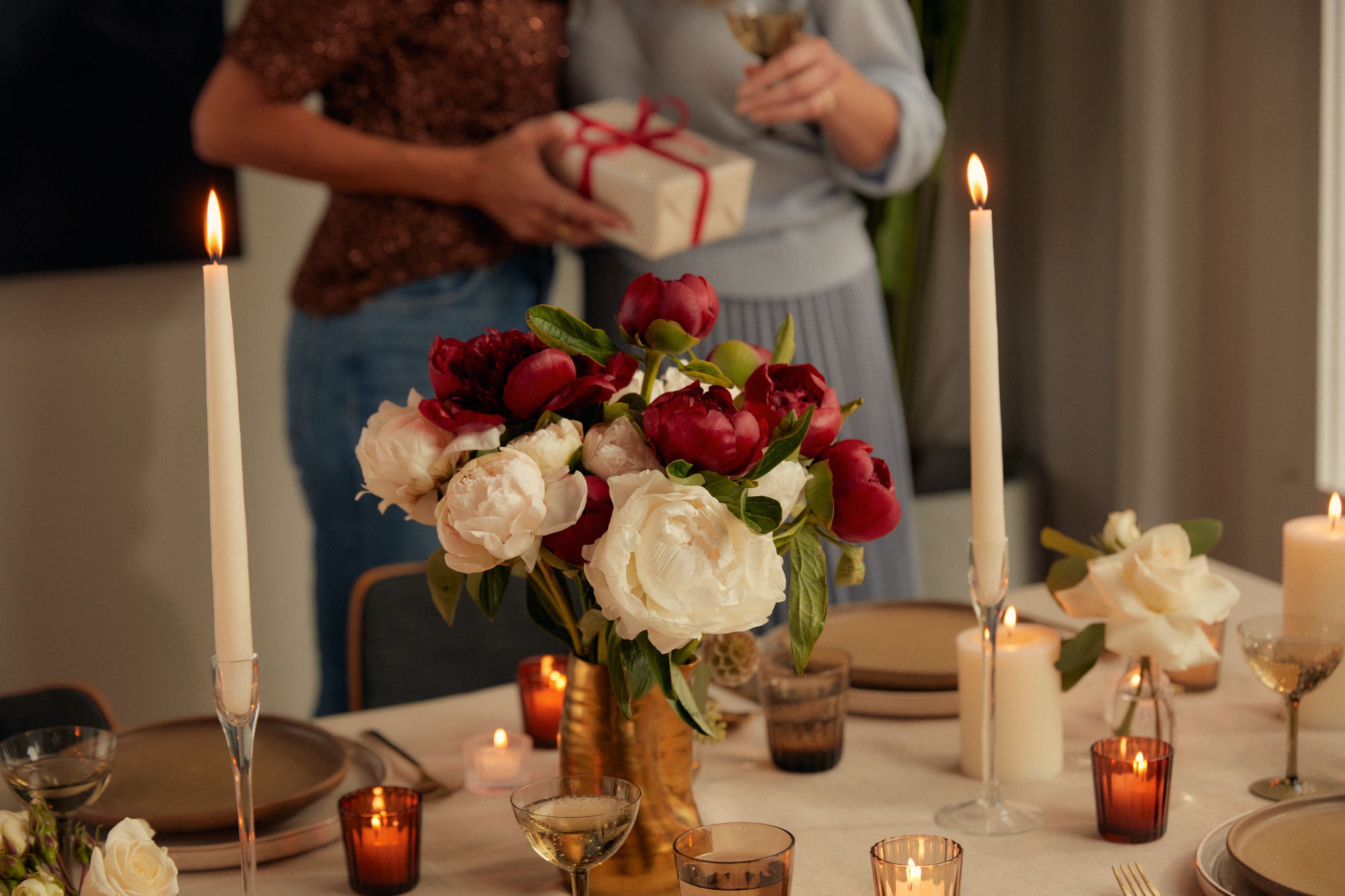 Holiday party hosts exchanging gifts and a close-up of UrbanStems bouquet, The Claus.