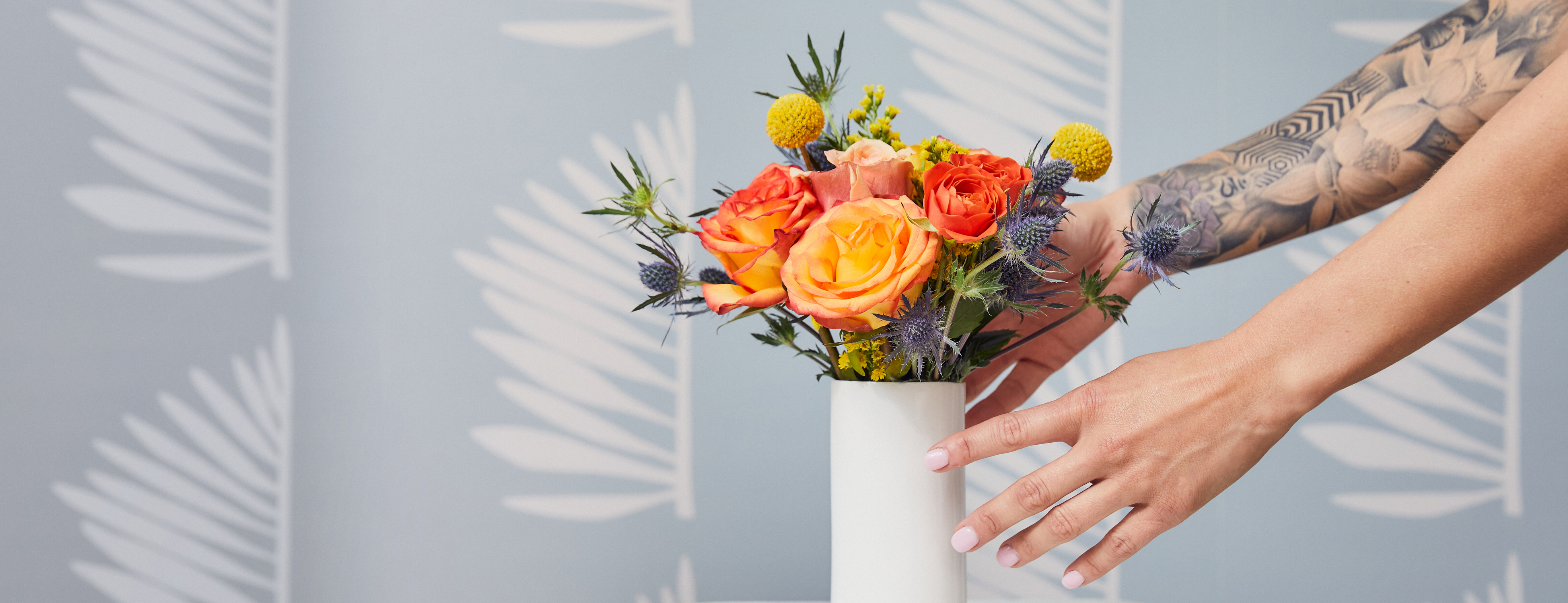 Hands placing a mini flower bouquet in a white vase