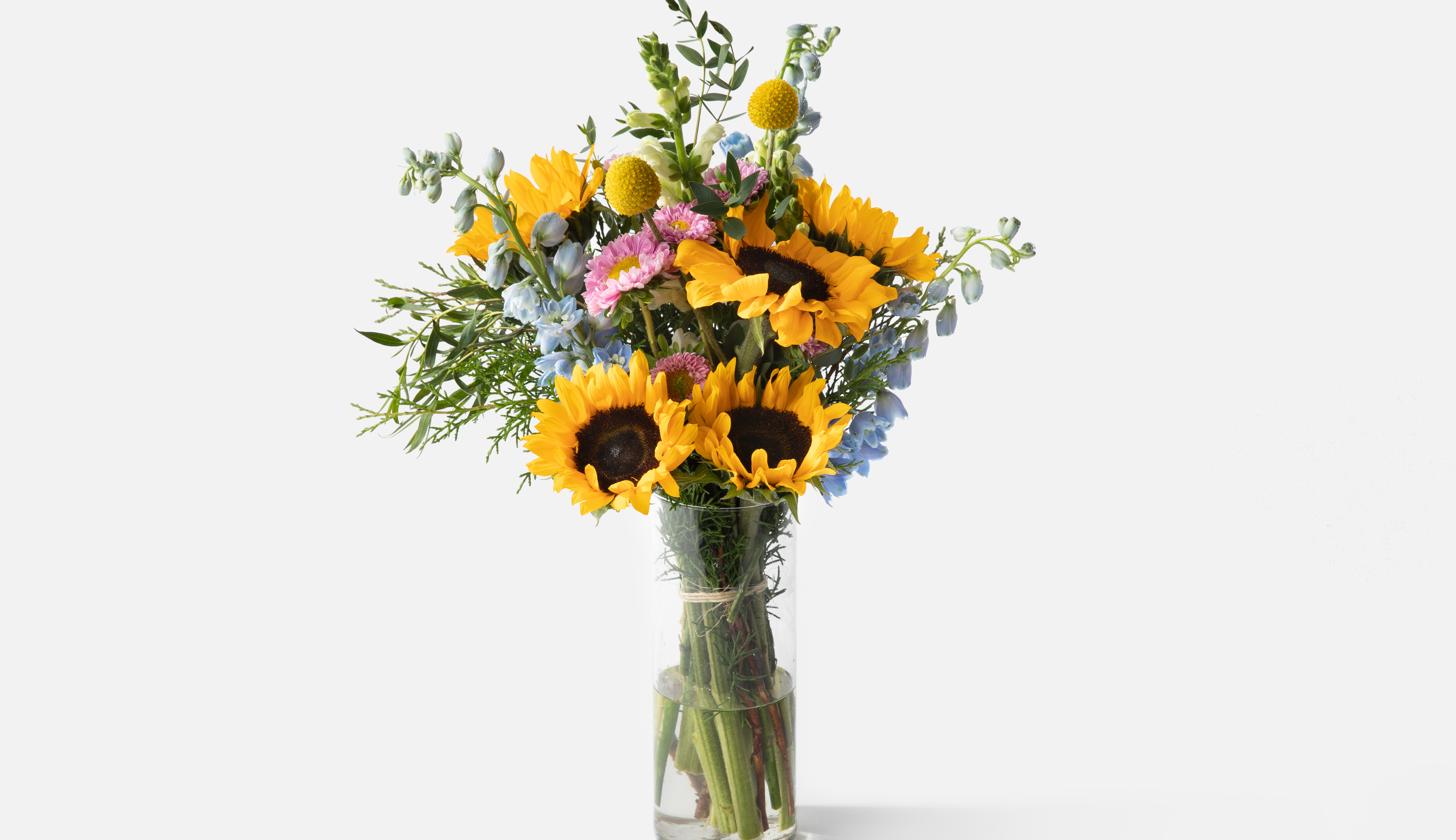 Bouquet with sunflowers and other florals in glass vase.