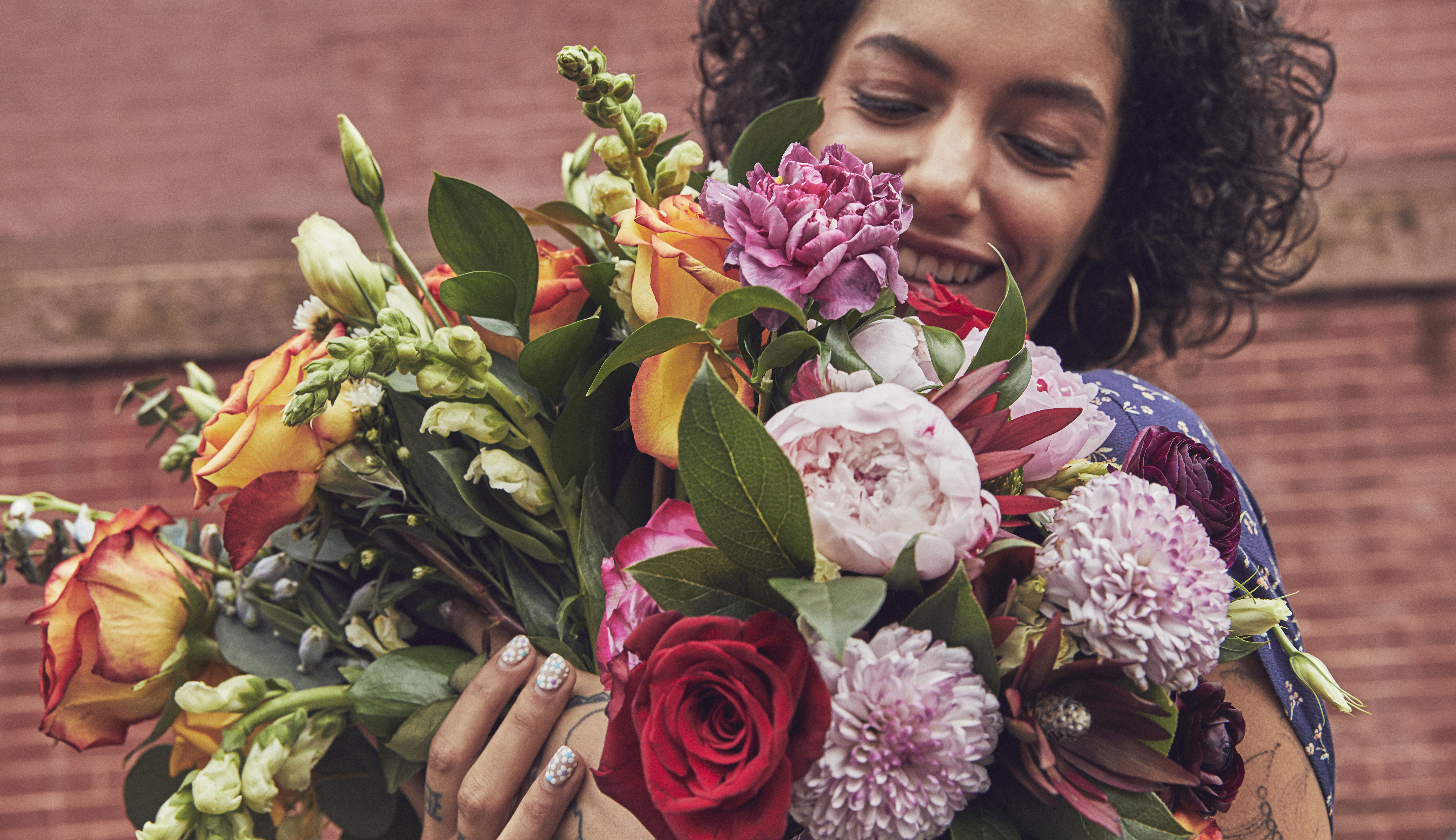 Woman holding an armful of floral bouquets