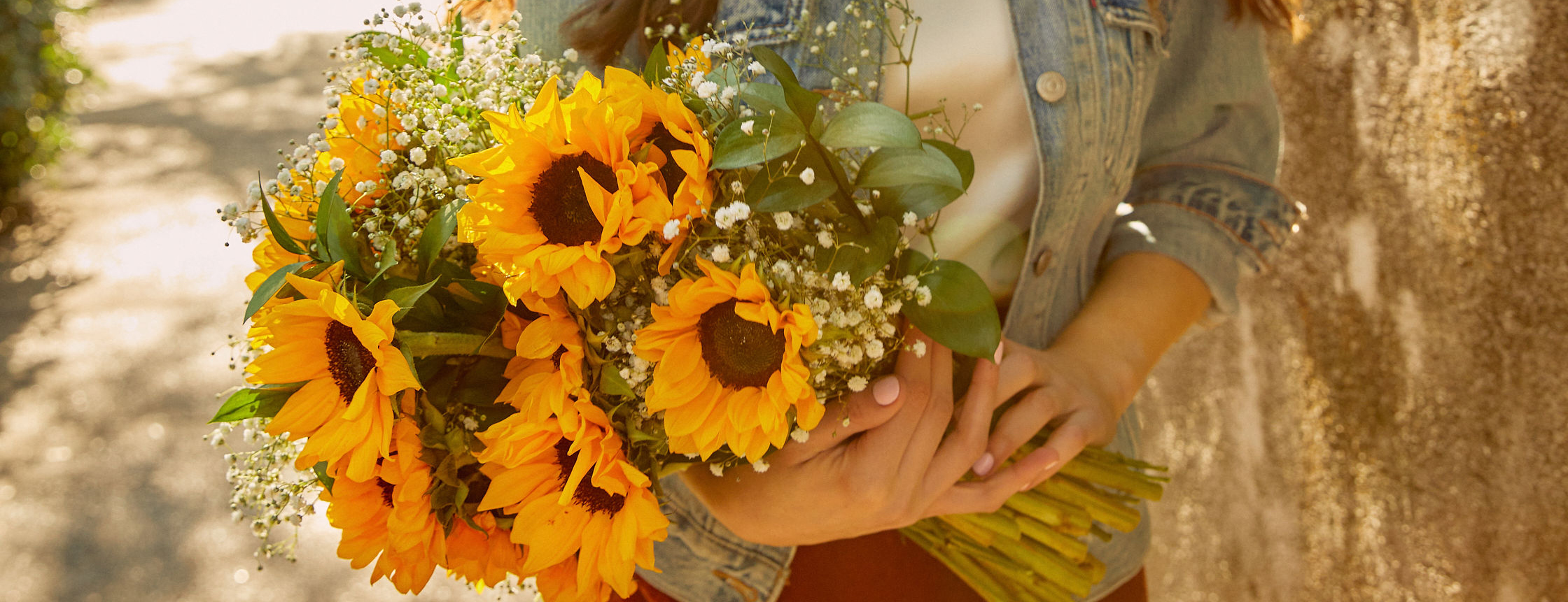 Woman holding sunflower bouquet at golden hour