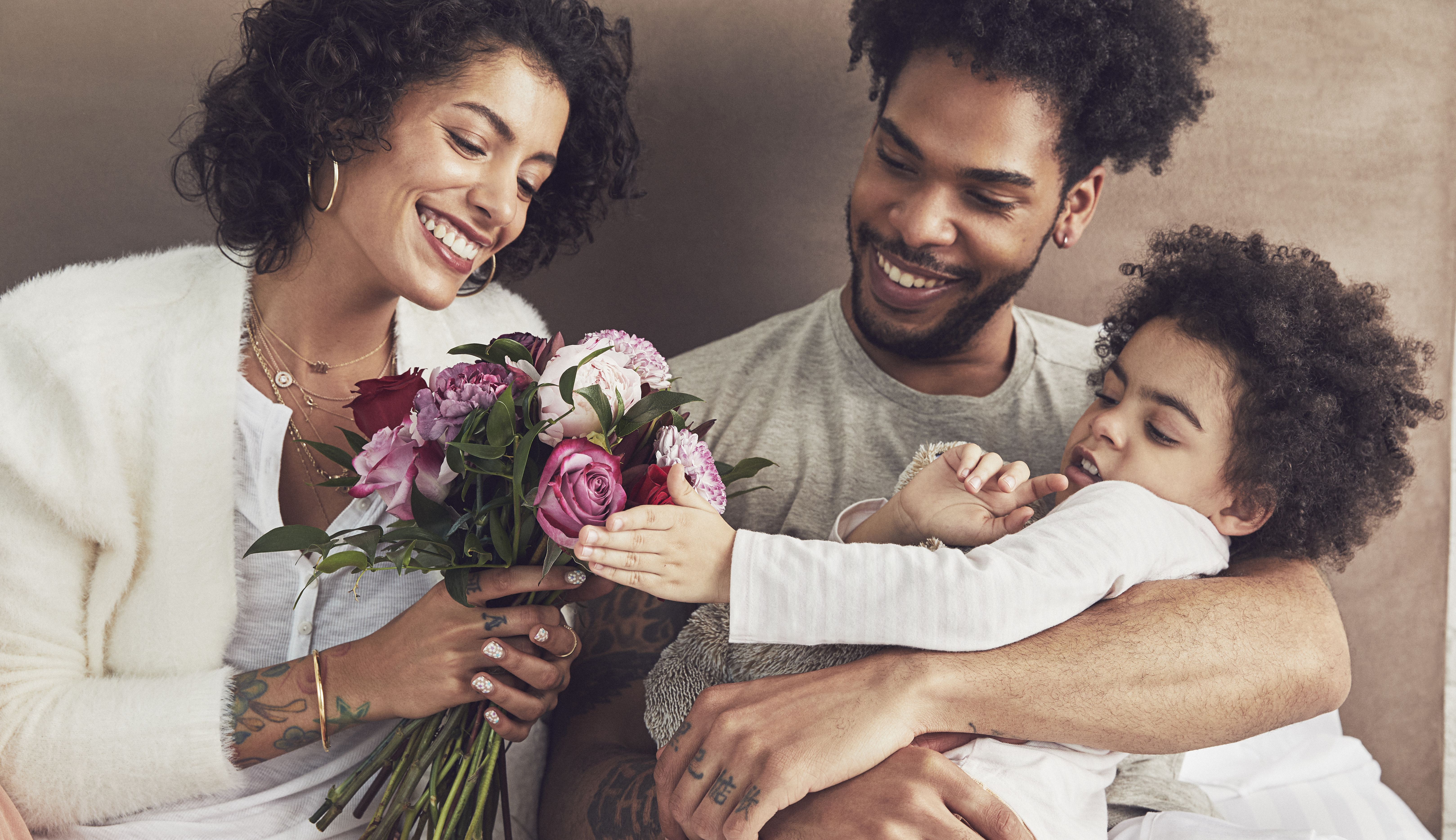 Family sitting in bed with a floral bouquet