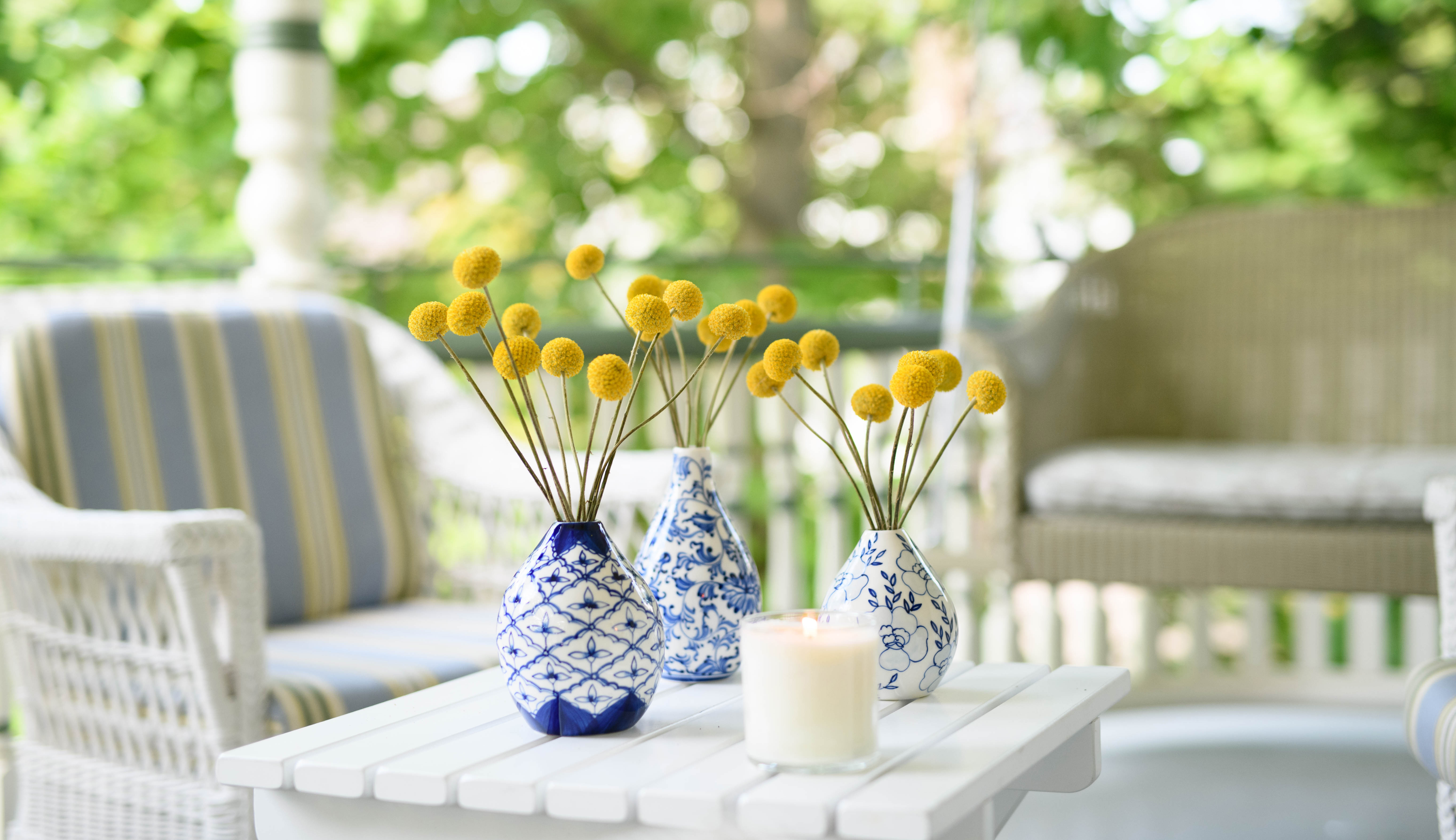 Three blue and white ceramic vases with yellow flowers on an outdoor patio
