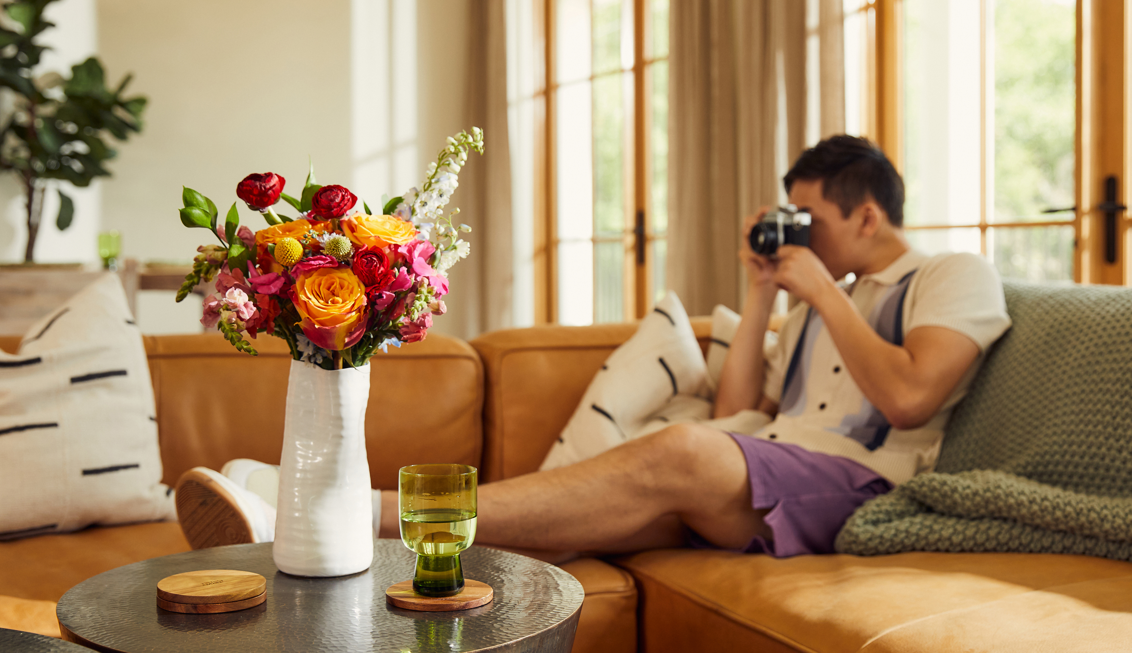 Man relaxing on a couch with a bouquet fo fresh flowers on the coffee table