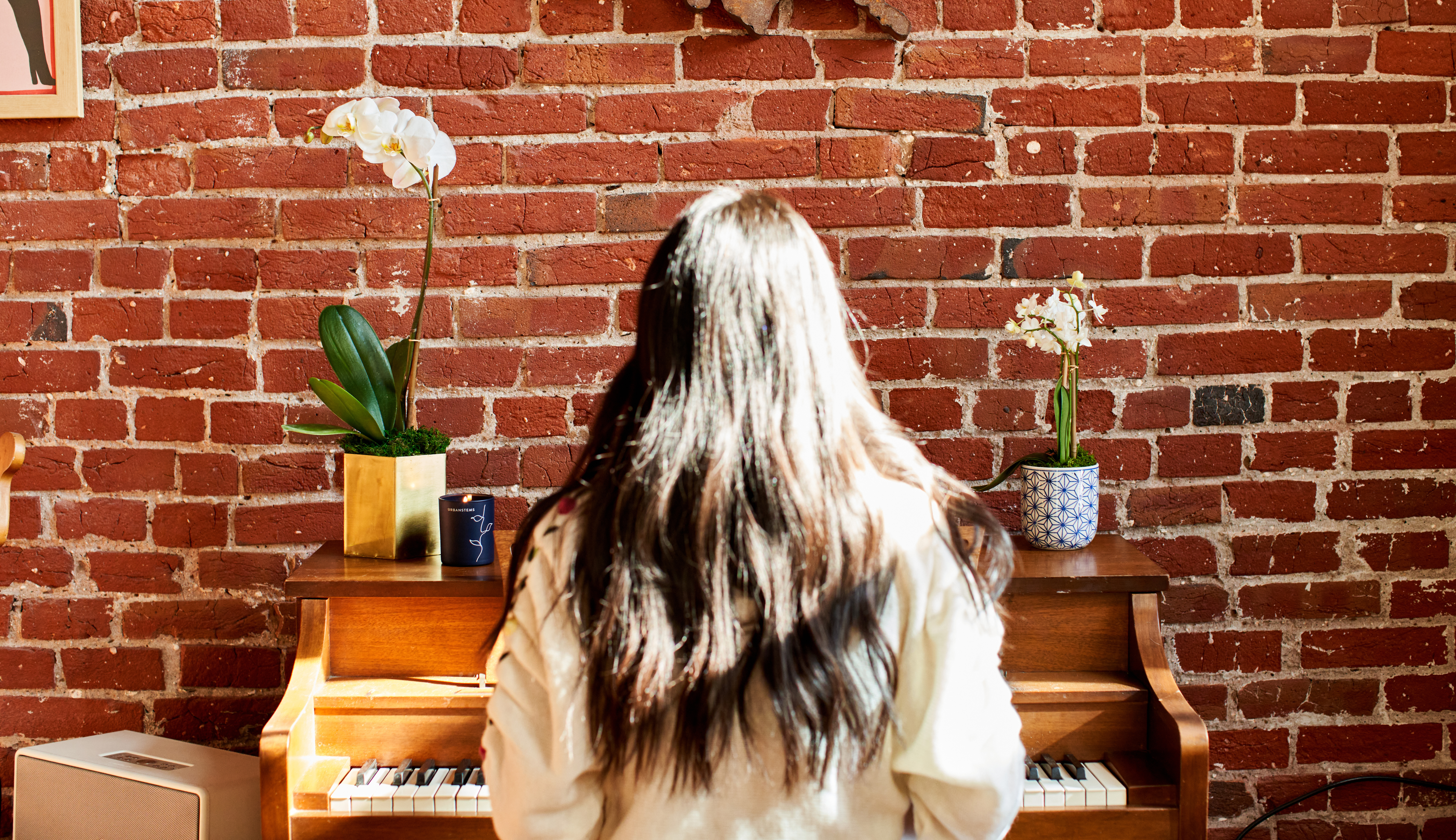 Woman playing piano with orchid plants on top