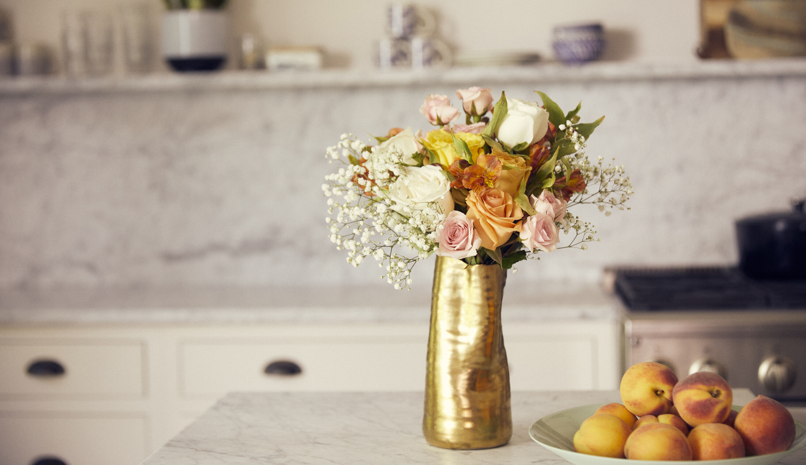 Bouquet of flowers in a gold vase on countertop