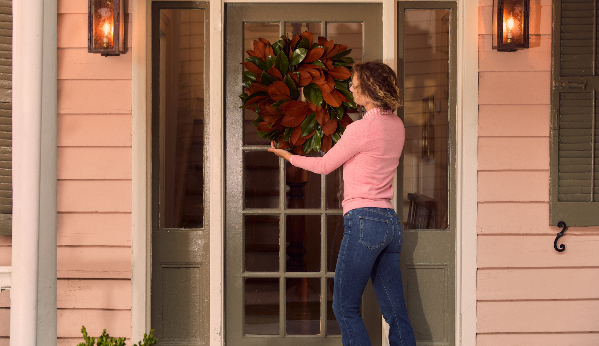 Woman hanging wreath with magnolia leaves on door