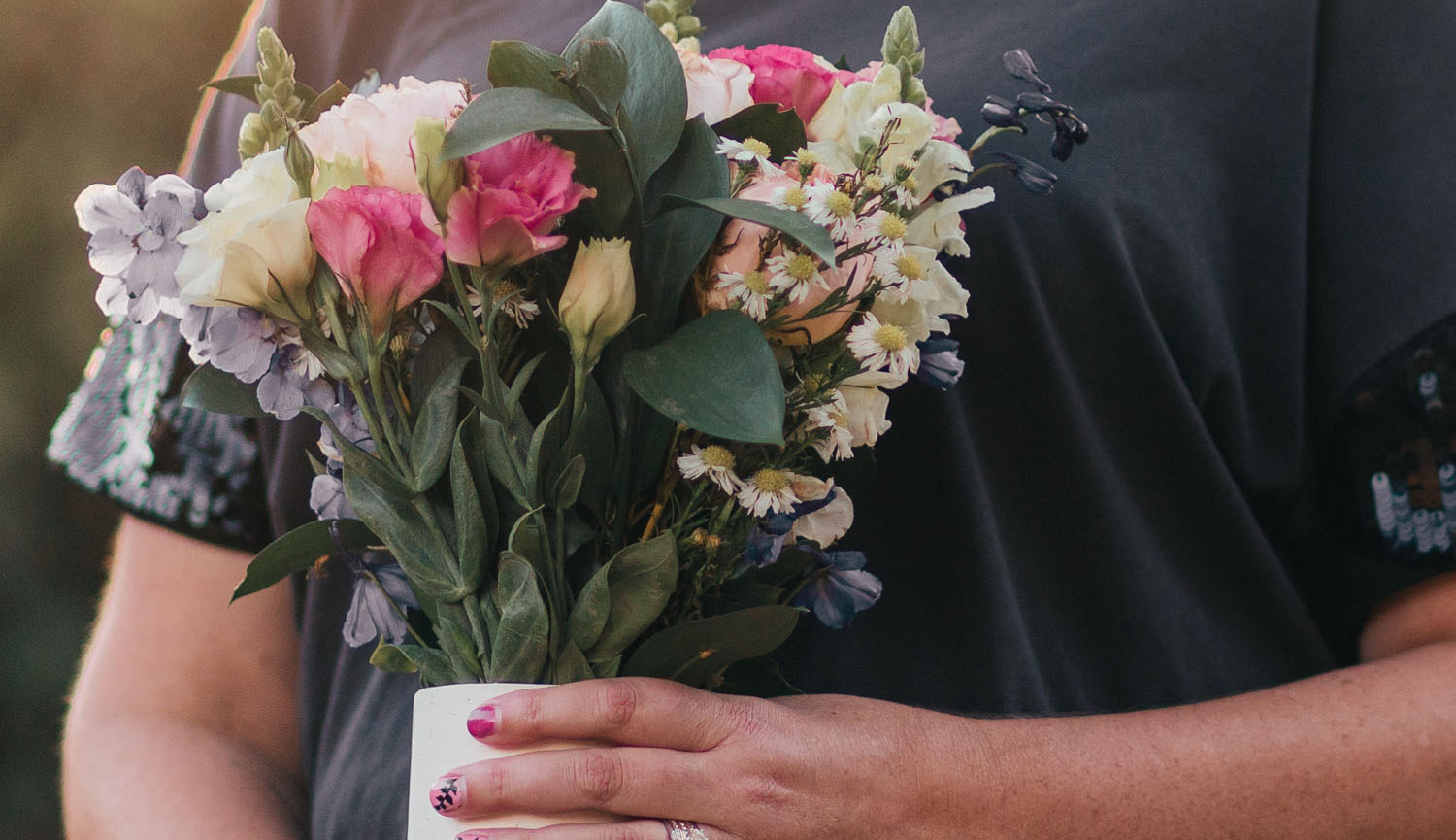 Hands holding a vase with a floral bouquet