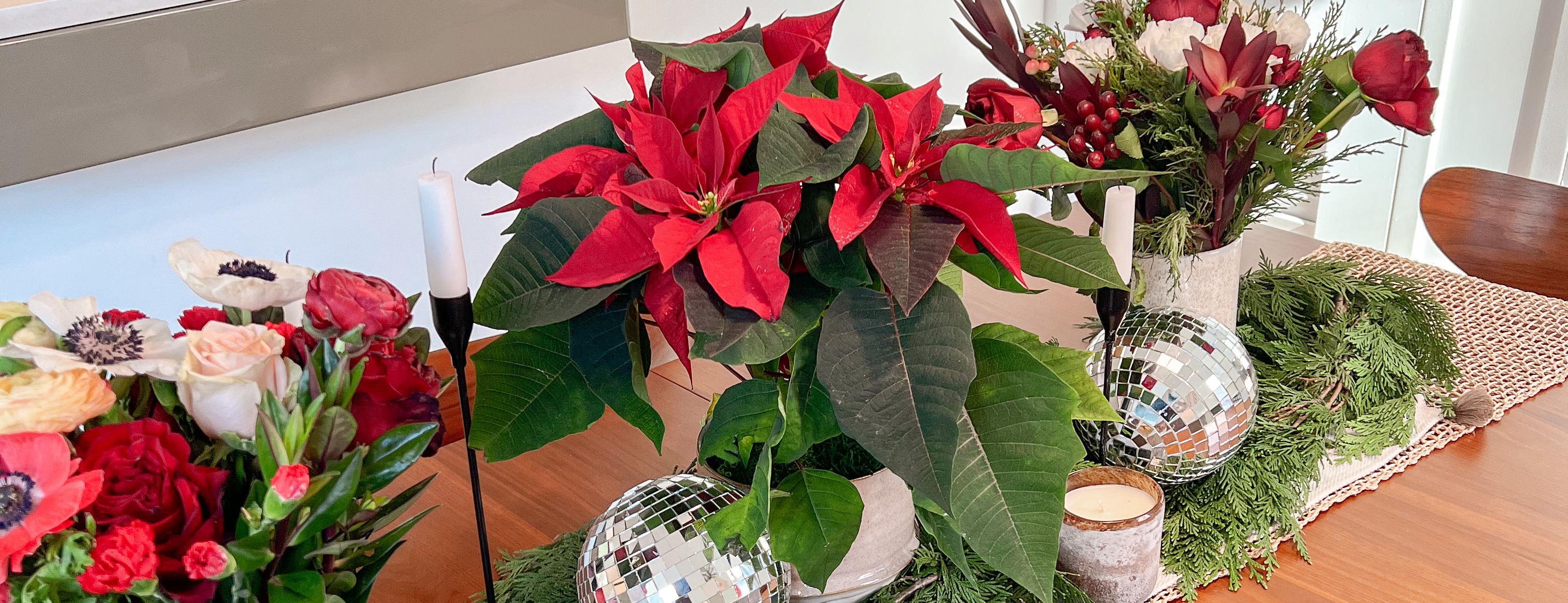 Table decorated with holiday centerpieces featuring poinsettia plants
