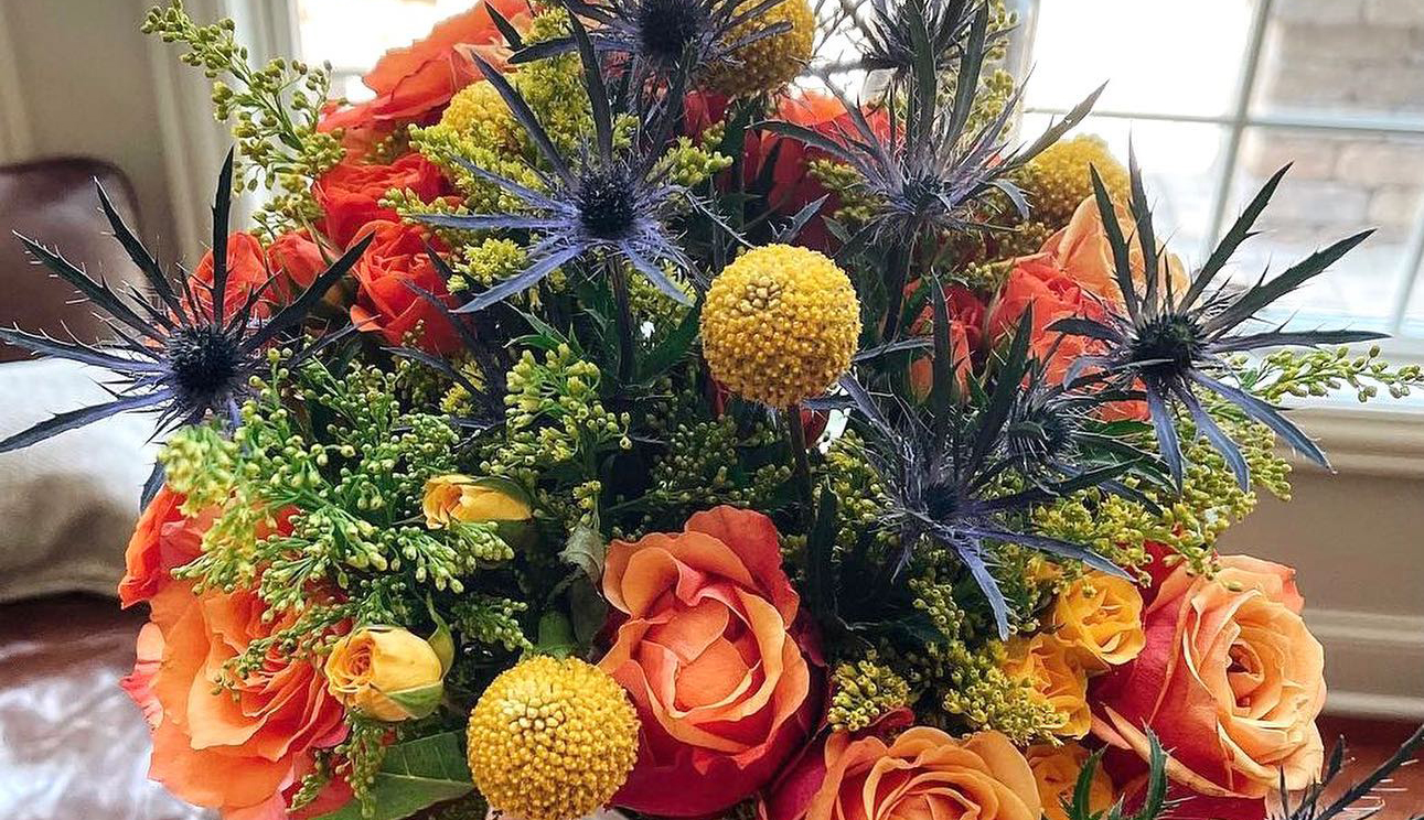 Close up of trendy orange and blue flowers, featuring roses and thistle