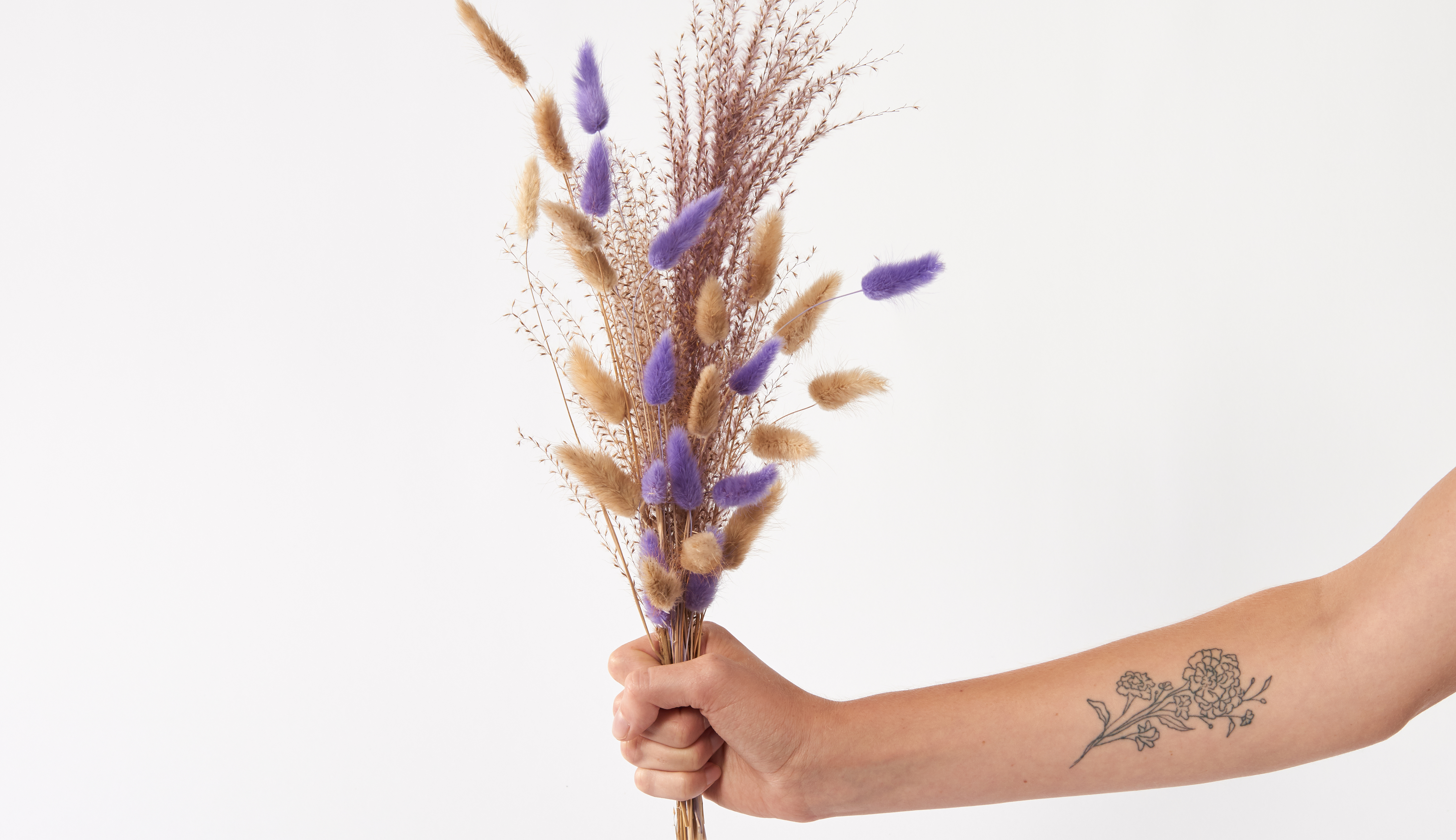 Hand holding a dried bouquet with purple accents