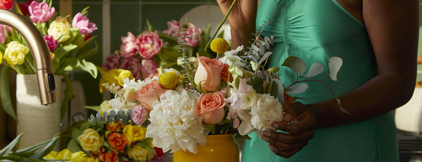 Woman holding bright flowers in spring colors in her kitchen