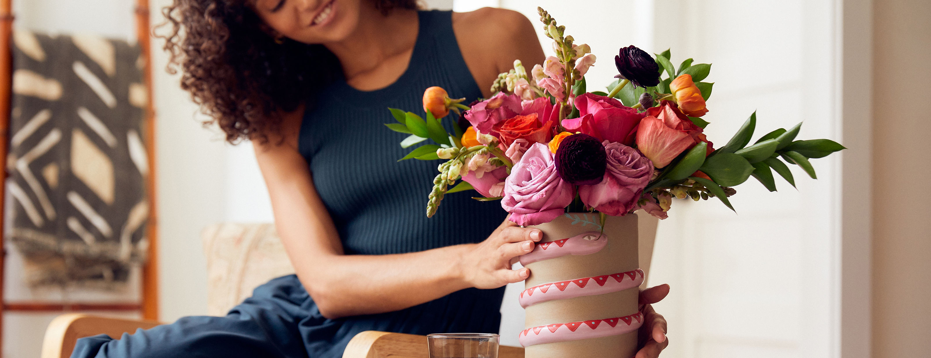 Woman decorating her home with summer flowers. Send summer flowers online with UrbanStems.
