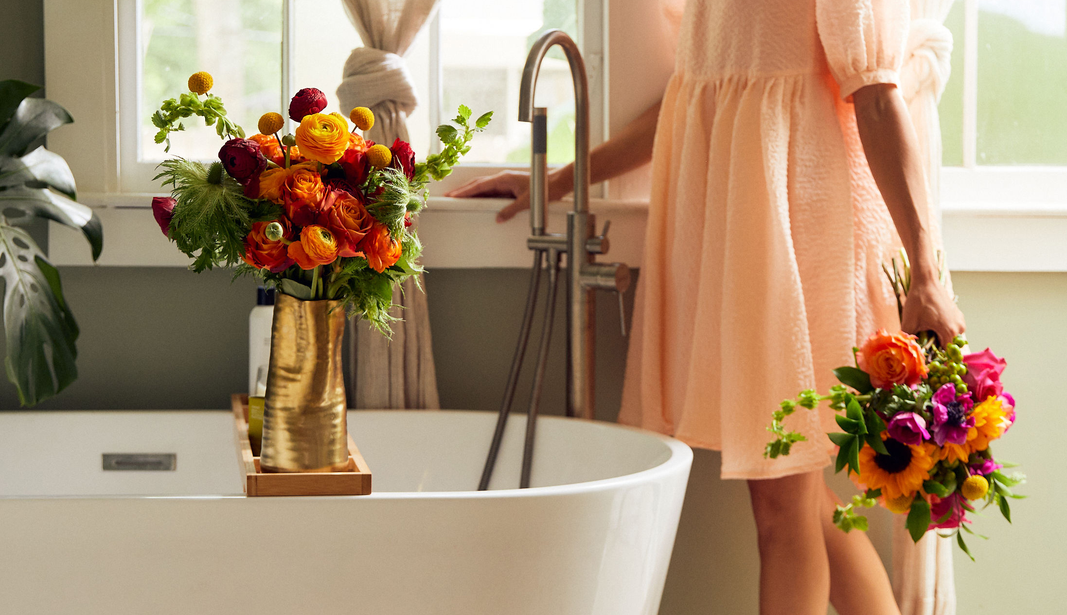 Woman decorating her  bathroom with summer flowers, available for next day flower delivery.