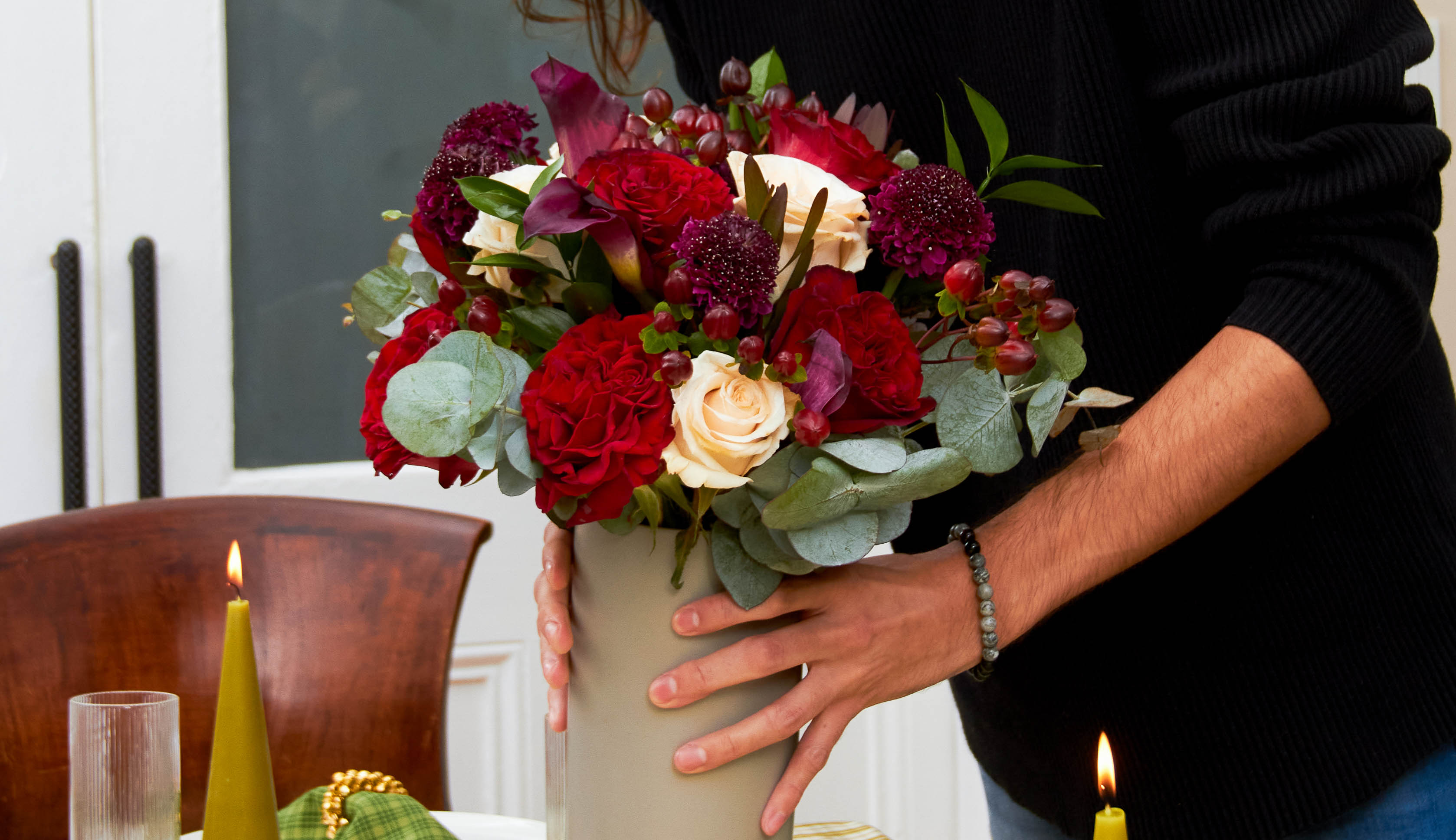 Hand placing 2022 Christmas flowers onto a table set for the holidays