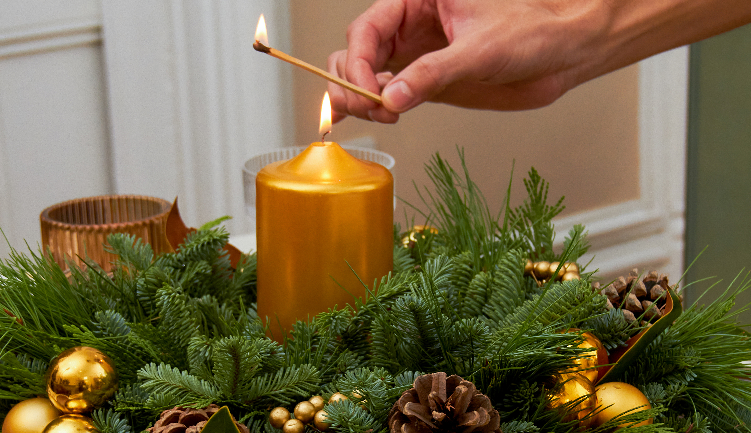 Hand lighting a candle on a holiday centerpiece. 