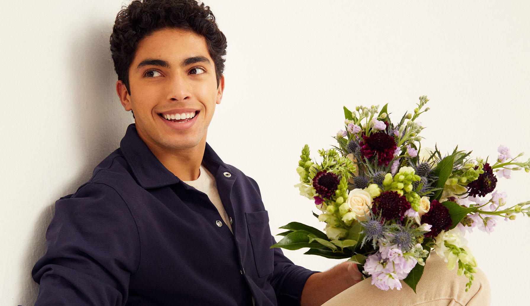 Man holding dark purple flower bouquet for Valentines Day 2023